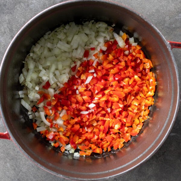 Peppers and onions frying in a pan.