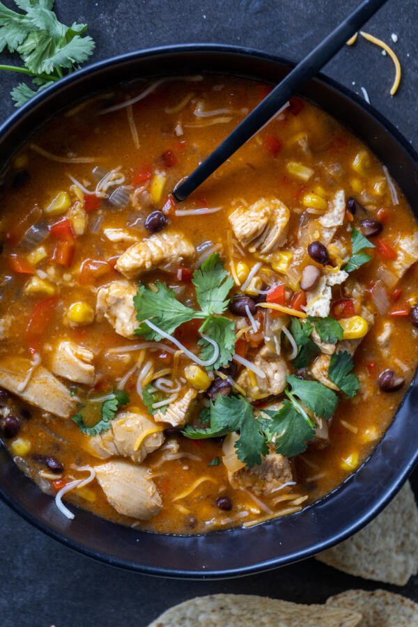 Chicken Enchilada Soup in a bowl with a spoon. 