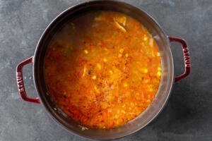Corn and beans added to the cooking pot of soup.
