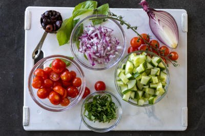 Veggies cut up in bowl on a cutting board.