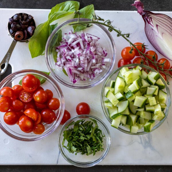 Veggies cut up in bowl on a cutting board.