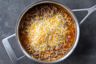 Ground beef in a pan with Enchiladas sauce and cheese.