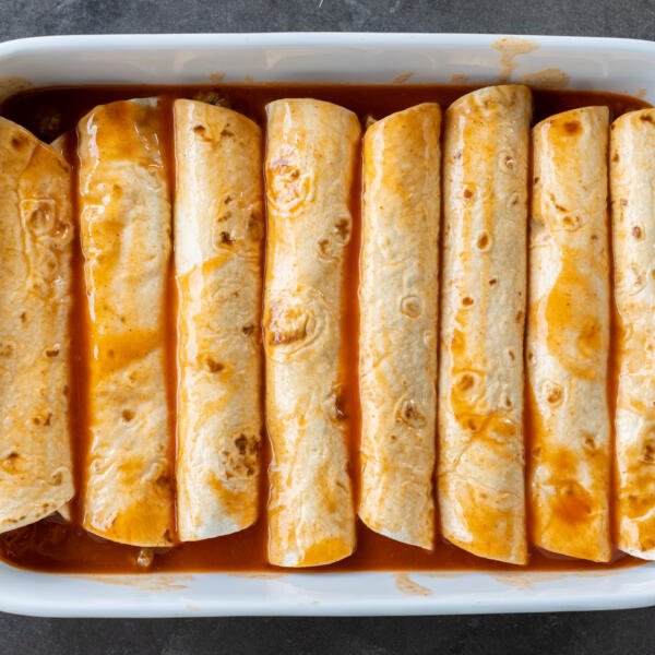 Ground Beef Enchiladas with sauce on top.