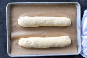 Two poppy seed rolls on a baking sheet.