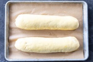 Brushed poppy seed rolls on a baking sheet.