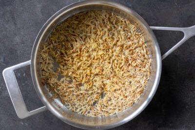 Browned orzo in a pan.