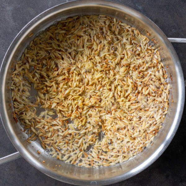 Browned orzo in a pan.