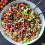 Antipasto Salad with Dressing and serving utensils.