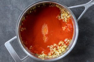 Tomato sauce with salt and onion in a pan.