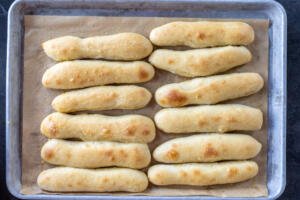Baked Olive Garden Breadsticks on a sheet with butter garlic.
