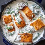 Salmon Florentine in a pan with creamy white sauce.