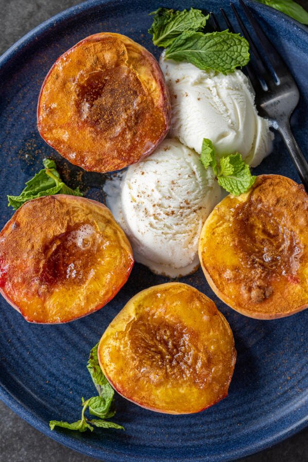 Air Fryer Peaches on a plate with ice cream.