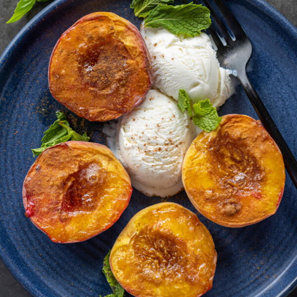 Air Fryer Peaches on a plate with ice cream.