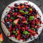 Pavlova with berries, cream and berry sauce.