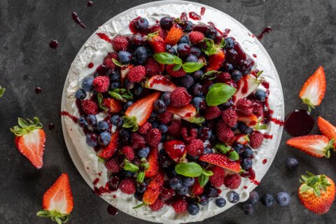 Pavlova with berries, cream and berry sauce.