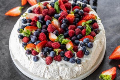 Pavlova topped with cream and berries.