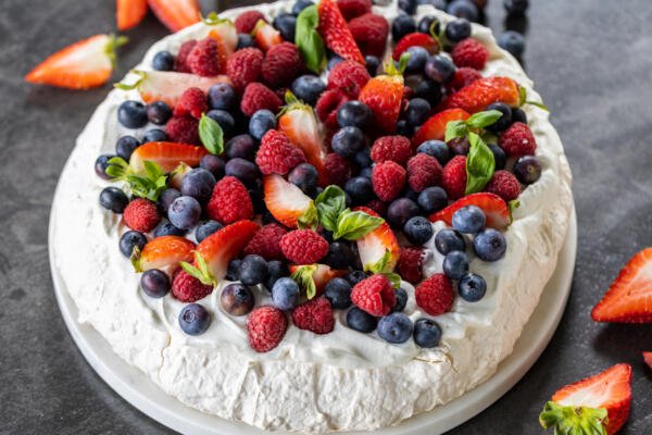 Pavlova topped with cream and berries.
