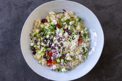 Greek Orzo Salad with Feta with dressing added to it.