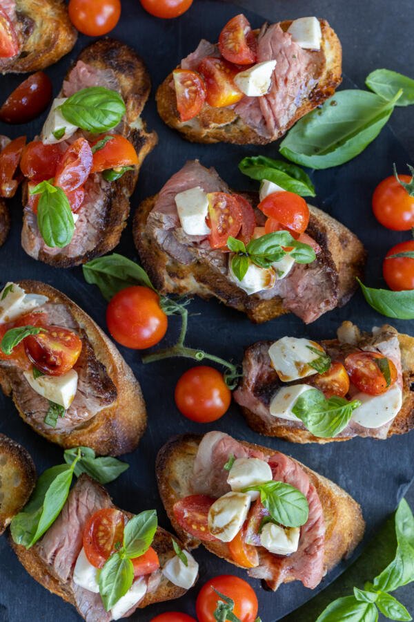 Steak Bruschetta with herbs on a serving tray.