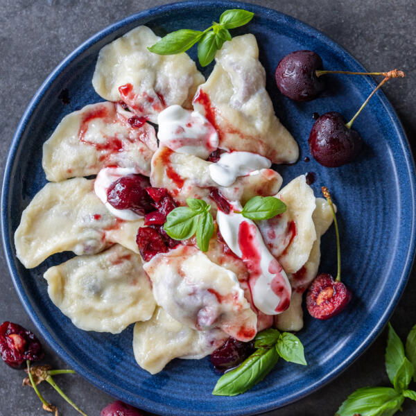 Plate with cherry vareniki and sour cream.