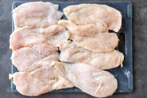 Seasoned chicken on a cutting board.