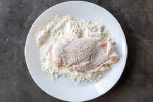 Chicken coated in flour on a plate.
