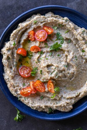 Eggplant salad in a plate with herbs and tomatoes.