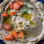 Eggplant salad in a plate with herbs on top.