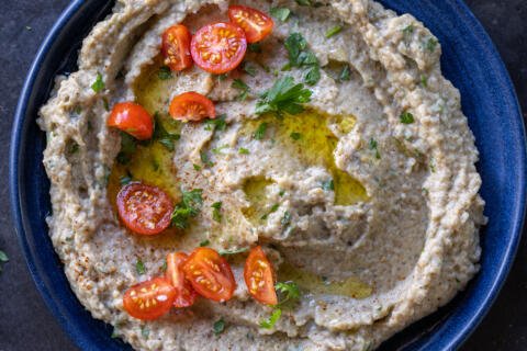 Eggplant salad in a plate with herbs on top.