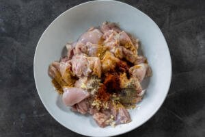 Chicken with all the seasonings in the a bowl.