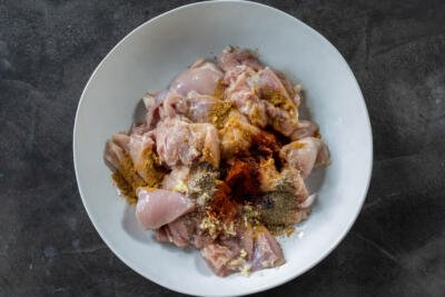 Chicken with all the seasonings in the a bowl.