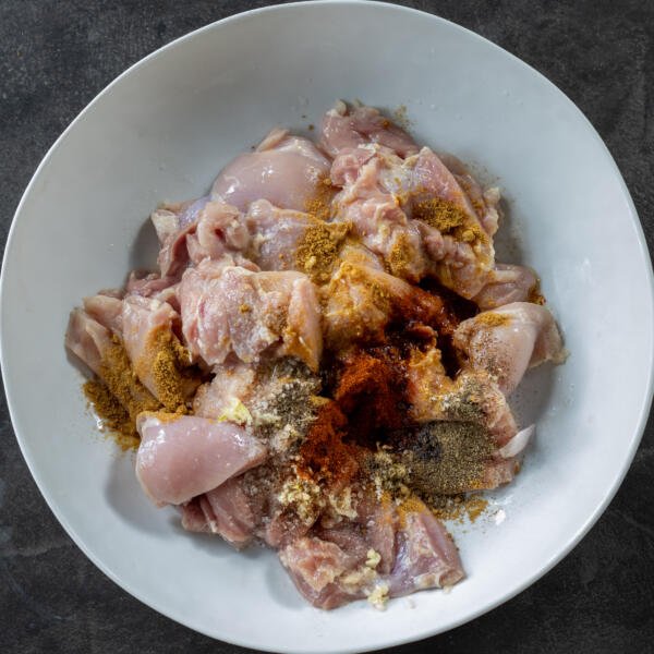 Chicken with all the seasonings in the a bowl.