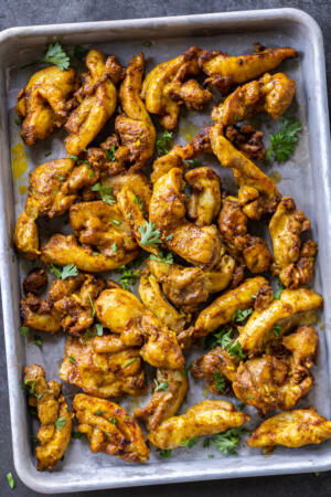 Sheet Pan Chicken Shawarma on a sheet pan with herbs.
