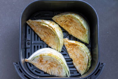 Seasoned cabbage in air fryer basket.