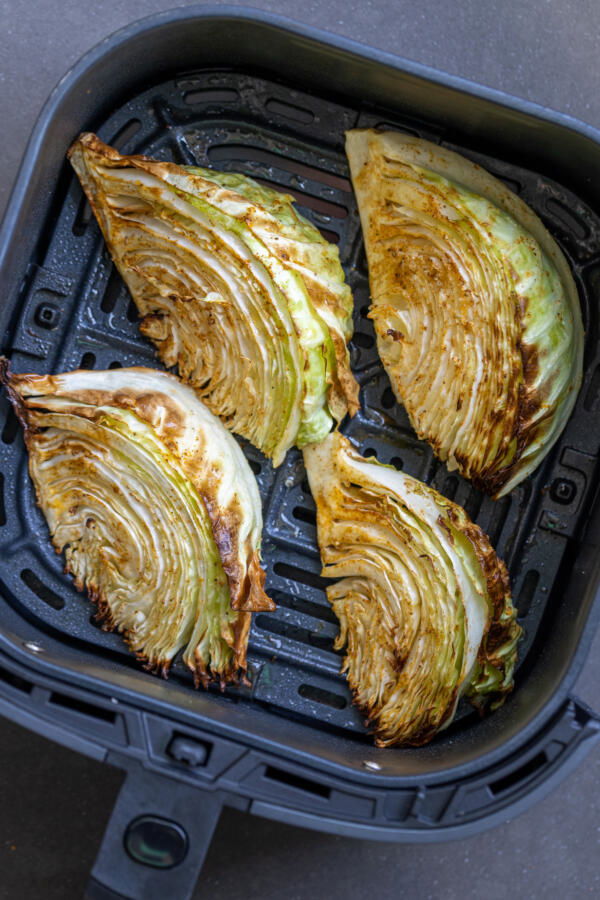 Air fryer basket with cabbage thats cooked.