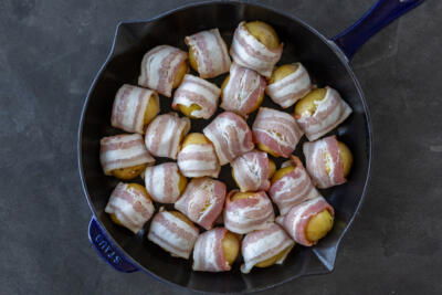 Bacon wrapped potatoes on a pan.