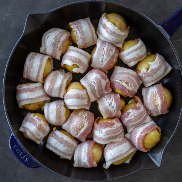 Bacon wrapped potatoes on a pan.