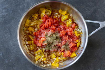 Tomatos added to bell pepper and onion and seaosning.