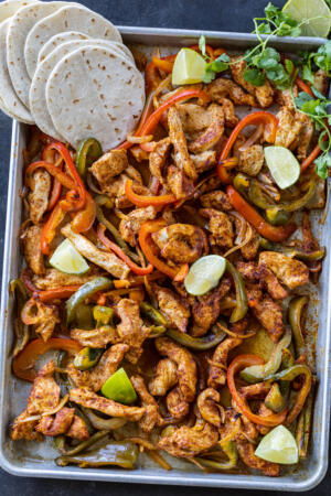 Chicken Fajitas on a sheet pan with tortillas.
