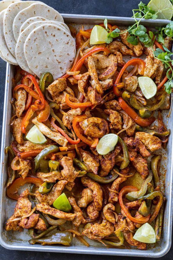 Chicken Fajitas on a sheet pan with tortillas.