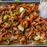 Chicken Fajitas on a sheet pan with tortillas.