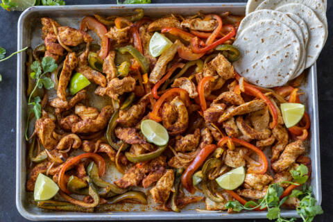 Chicken Fajitas on a sheet pan with tortillas.