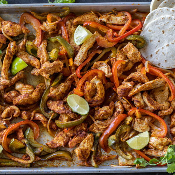 Chicken Fajitas on a sheet pan with tortillas.