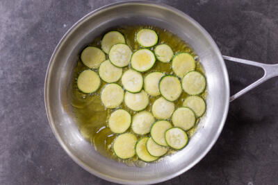 Fried sliced zucchini in a pan.