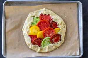 Tomato Galette on a baking sheet with seasned edges.