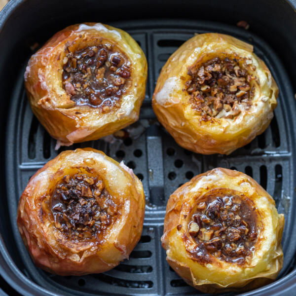 Apples in air fryer basket and nuts inside apples.