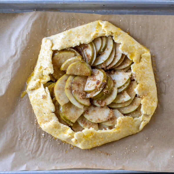Pear Galette on a baking sheet with edges brushed with egg wash.