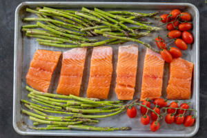 Salmon with veggies on a baking sheet.