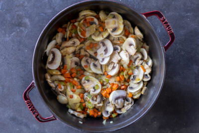 A pot with veggies with mushrooms.