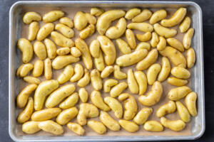 Potatoes facing down on a baking sheet.